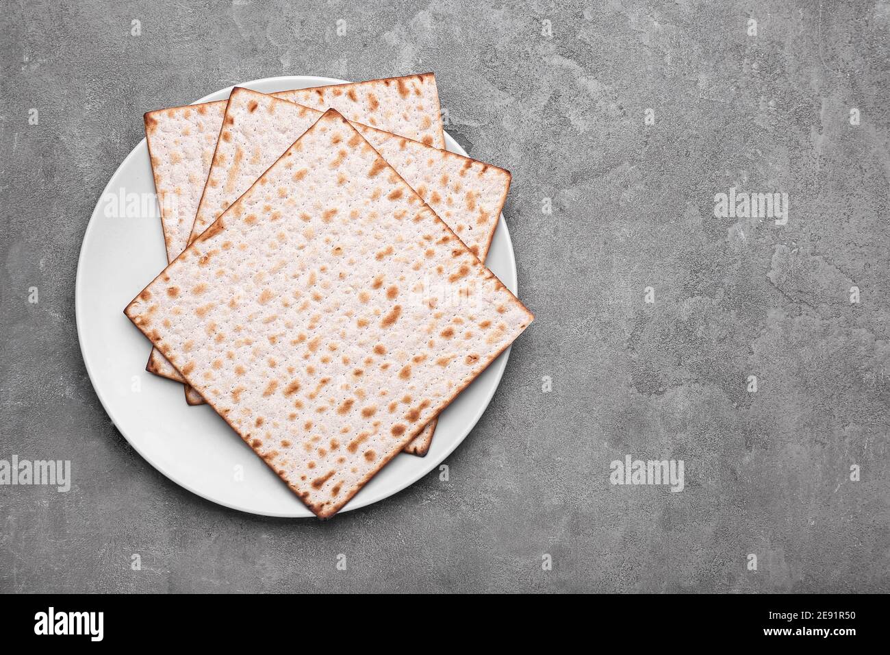 Plate with Jewish flatbread matza for Passover on grey background Stock