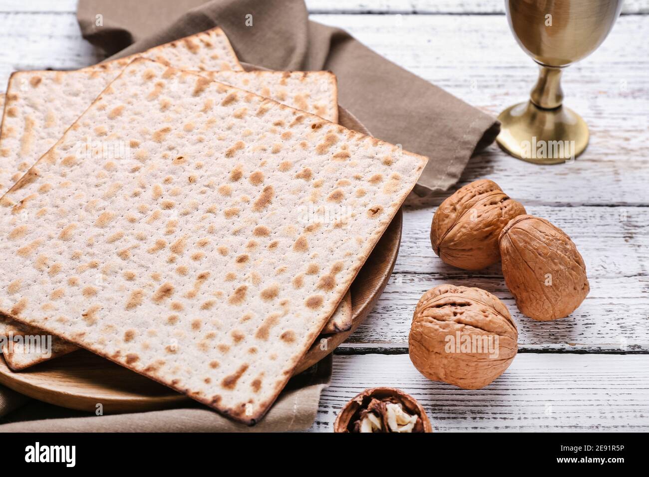 Plate with Jewish flatbread matza for Passover and walnuts on wooden