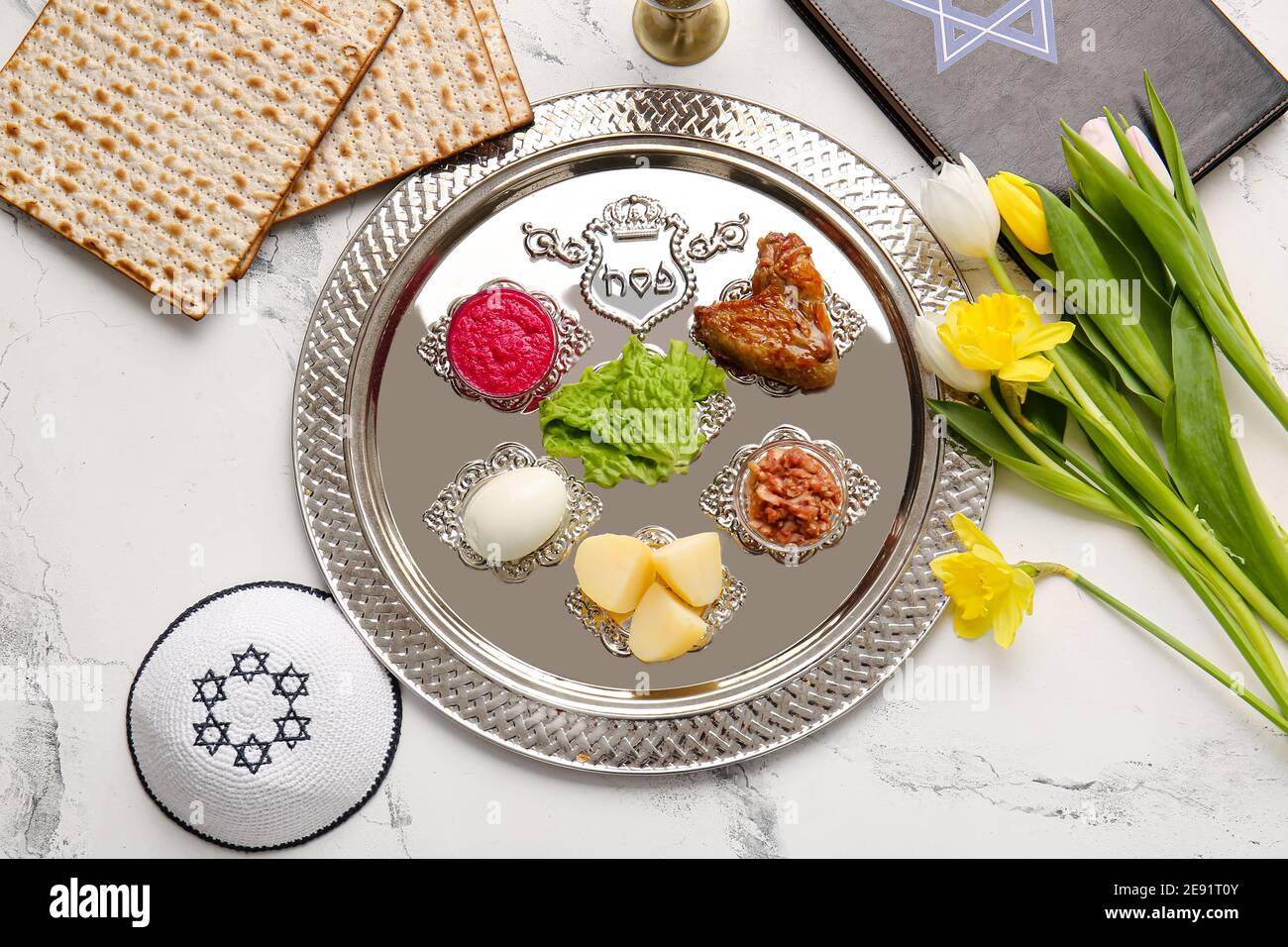 Passover Seder plate with traditional food, Torah and Jewish cap on