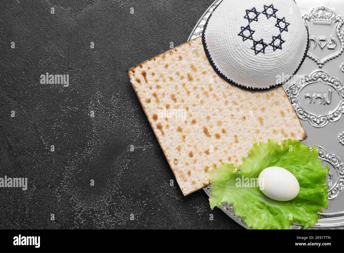 Passover Seder plate with traditional food and Jewish cap on dark ...