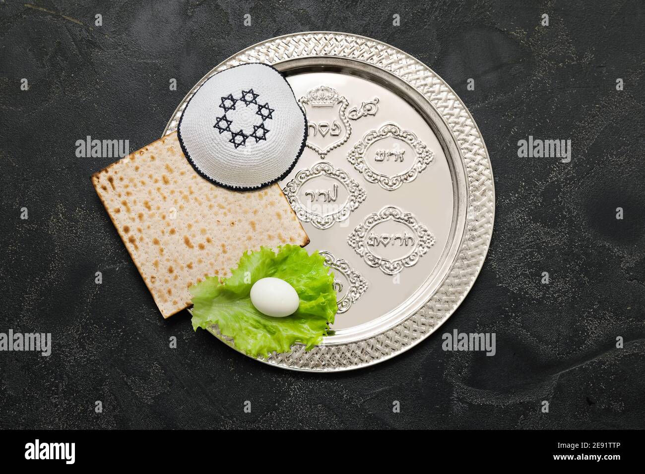 Passover Seder plate with traditional food and Jewish cap on dark ...