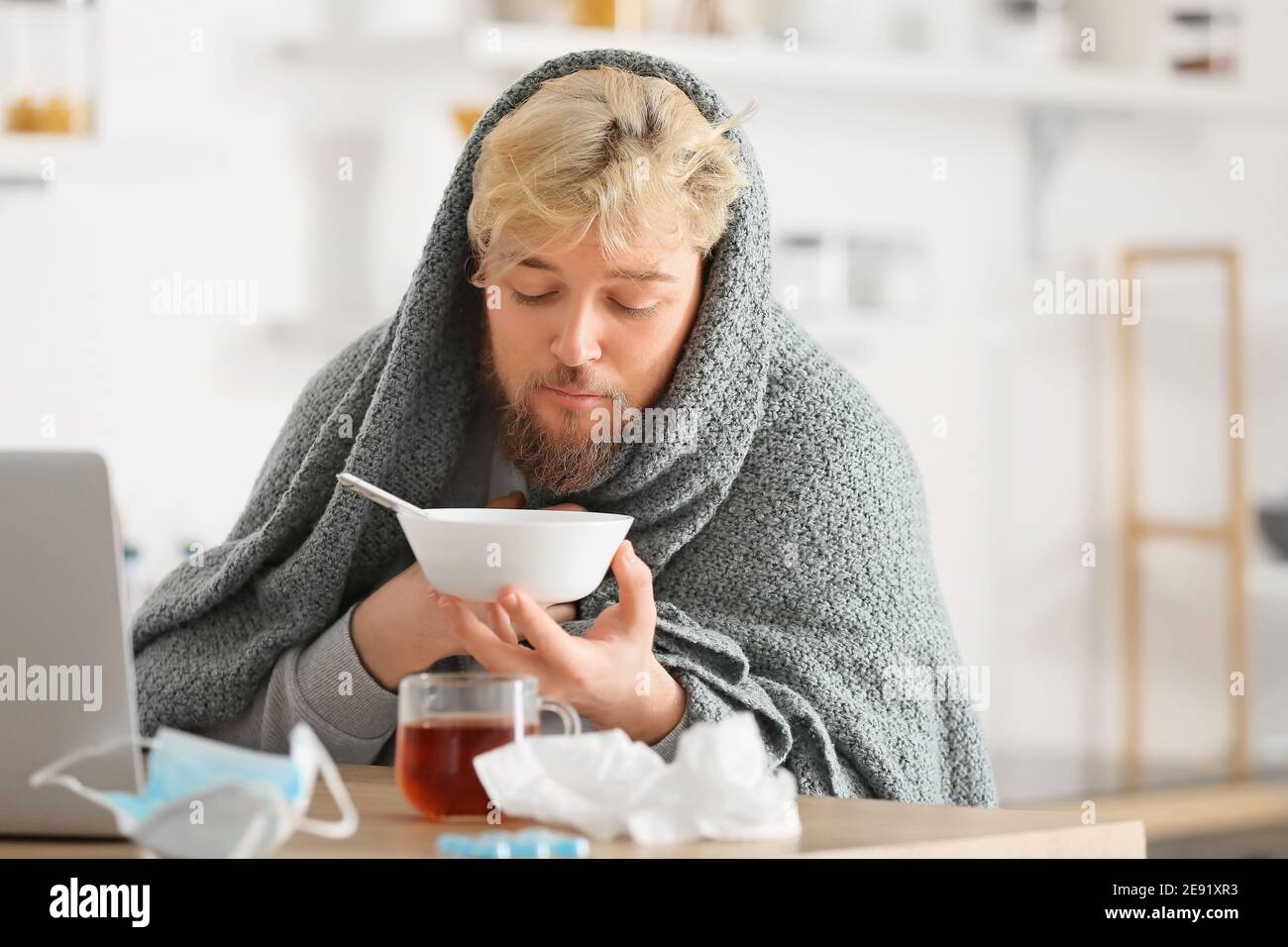 Sick young man eating chicken soup at home Stock Photo Alamy