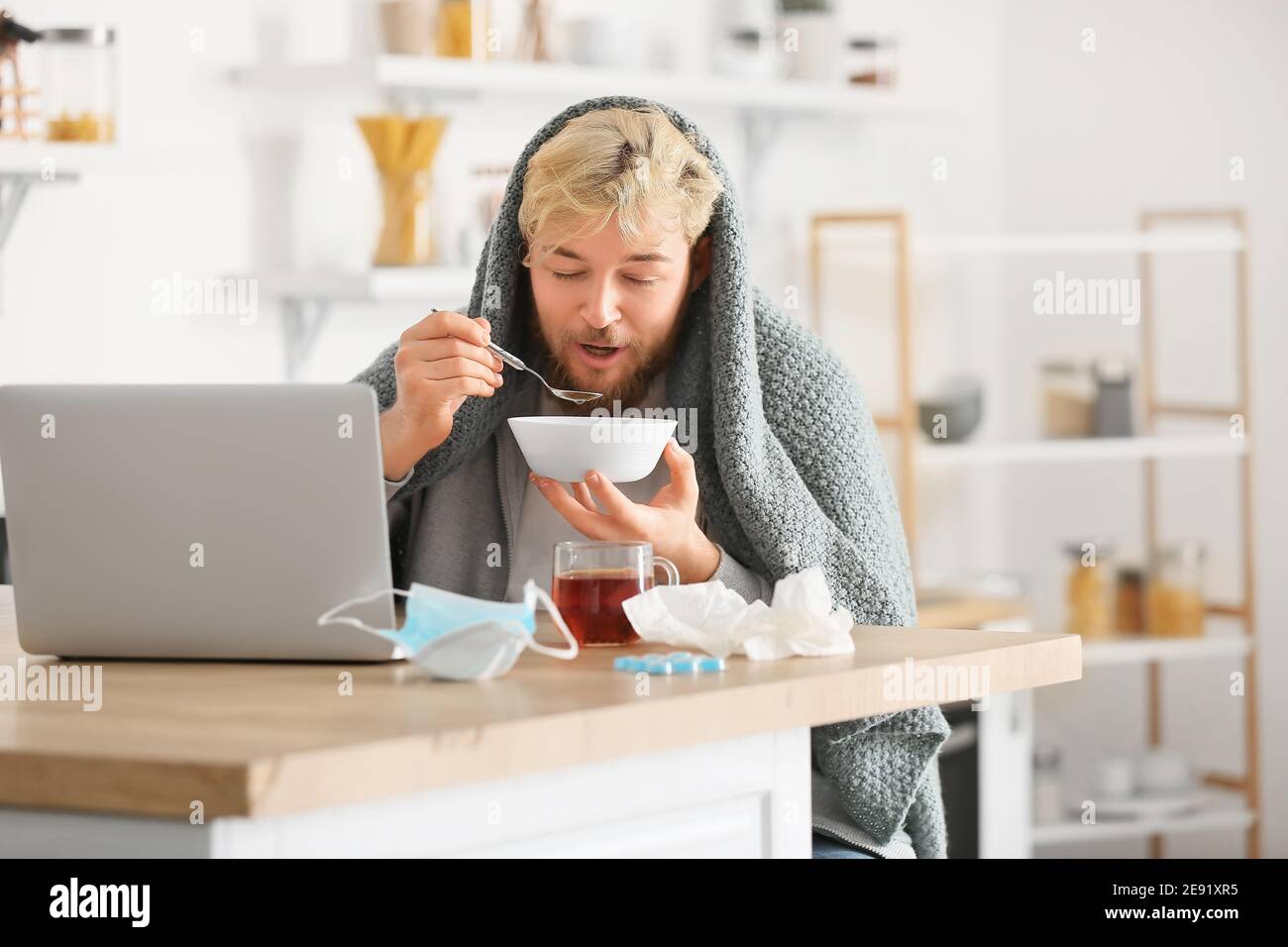 Sick young man eating chicken soup at home Stock Photo Alamy