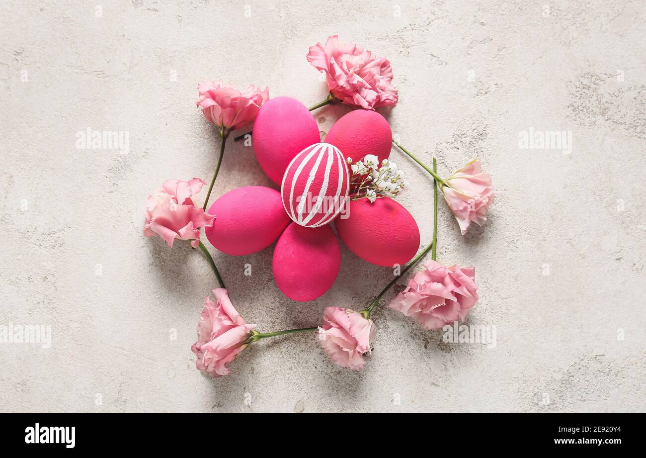 Composition with beautiful Easter eggs and flowers on light background ...