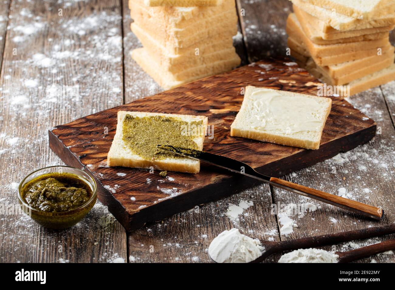 Spreading white bread slice with pesto sauce Stock Photo