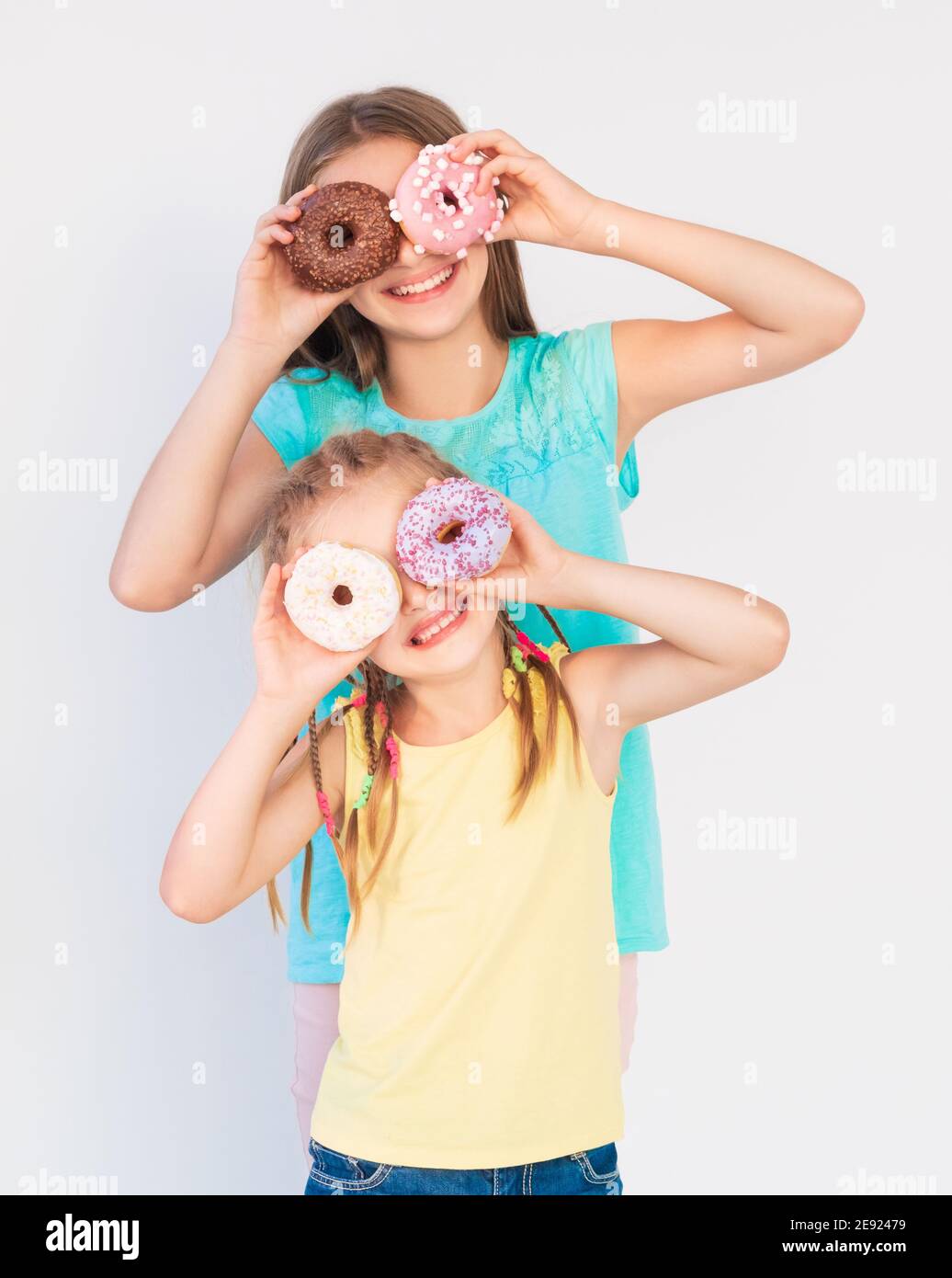 Two girls making funny jokes and joyful expressions using freshly baked  donuts Stock Photo - Alamy