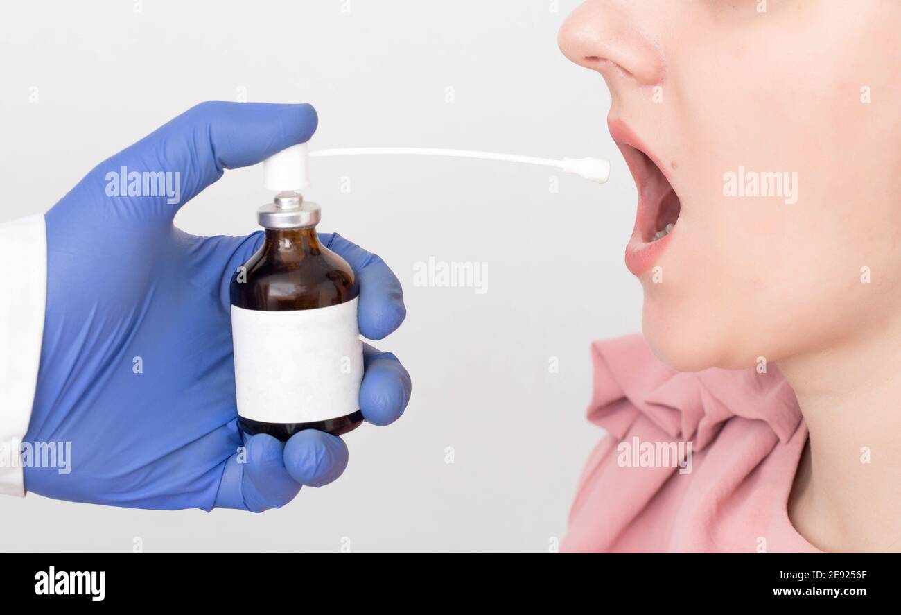 Doctor sprays antimicrobial and antiinflammatory spray into a girl's