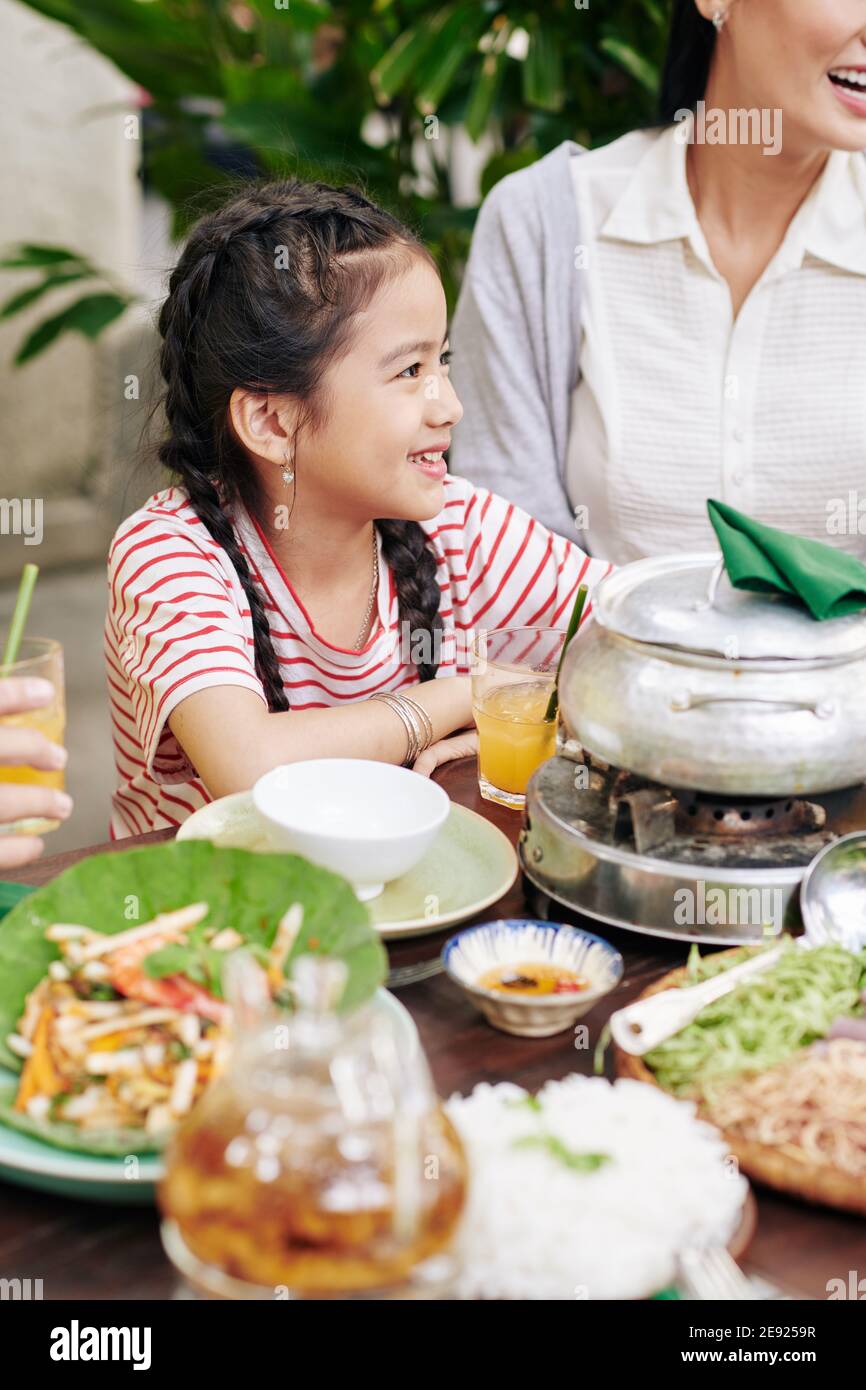 Girl sitting at dinner table with family Stock Photo