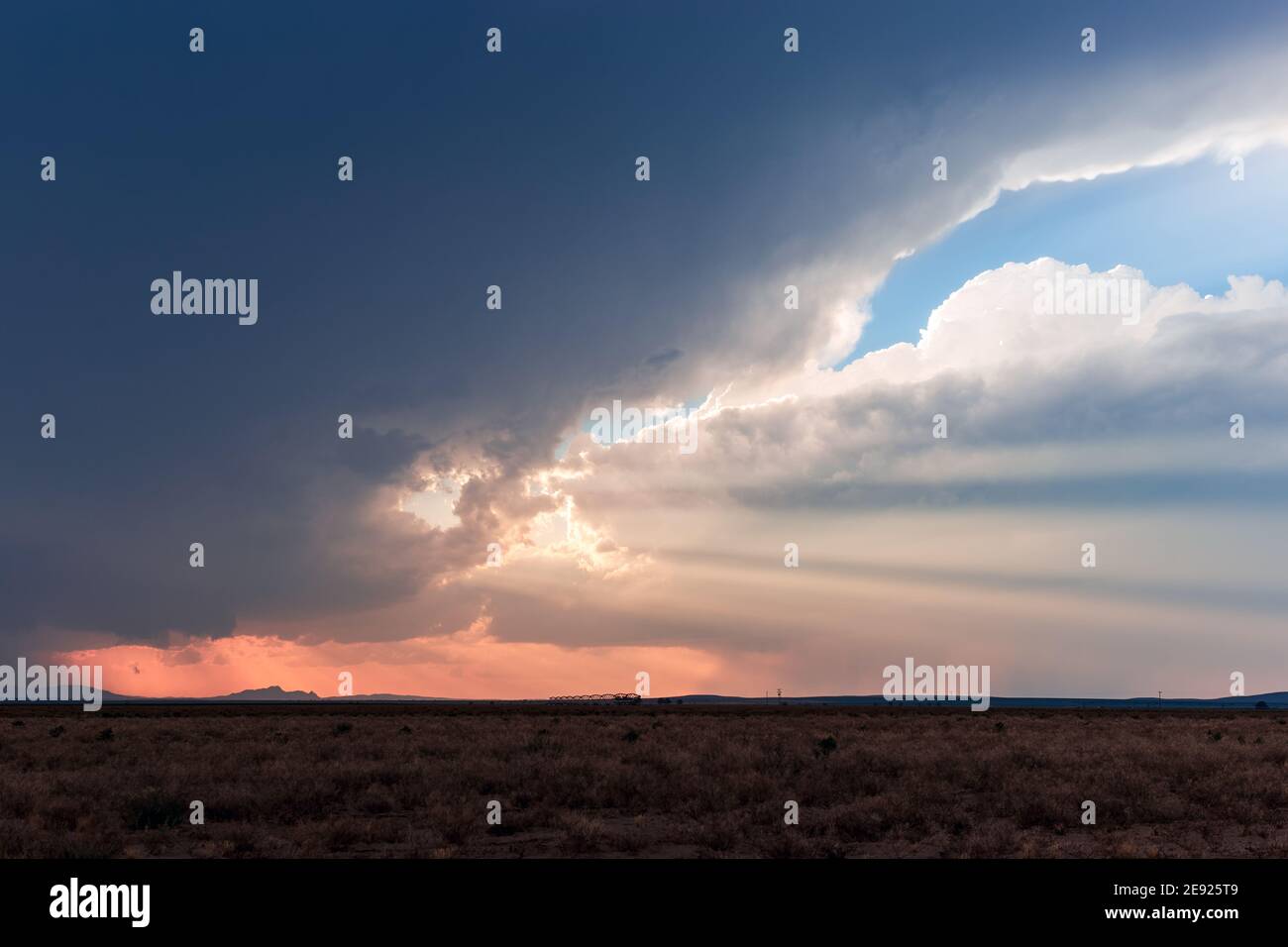 Crepuscular rays shining through dark storm clouds at sunset in the desert near Dell City, Texas Stock Photo