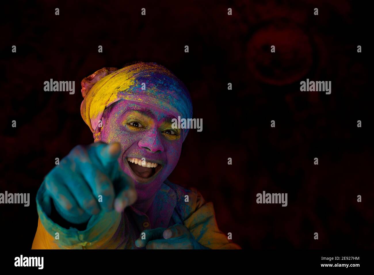 Man in turban smiling while dancing in excitement on Holi with gulal on his face Stock Photo