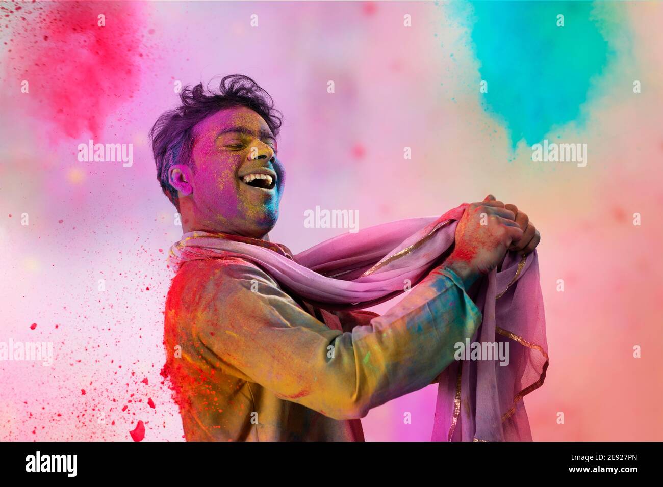 Man with gulal on his face dancing holding a dupatta in his hand during Holi celebration Stock Photo