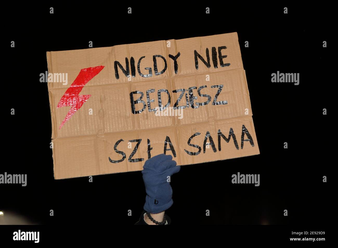Banner YOU WILL NEVER WALK ALONE and red lightning symbol holds by protesting girl during demonstration against to almost ban abortion in Poland. Stock Photo