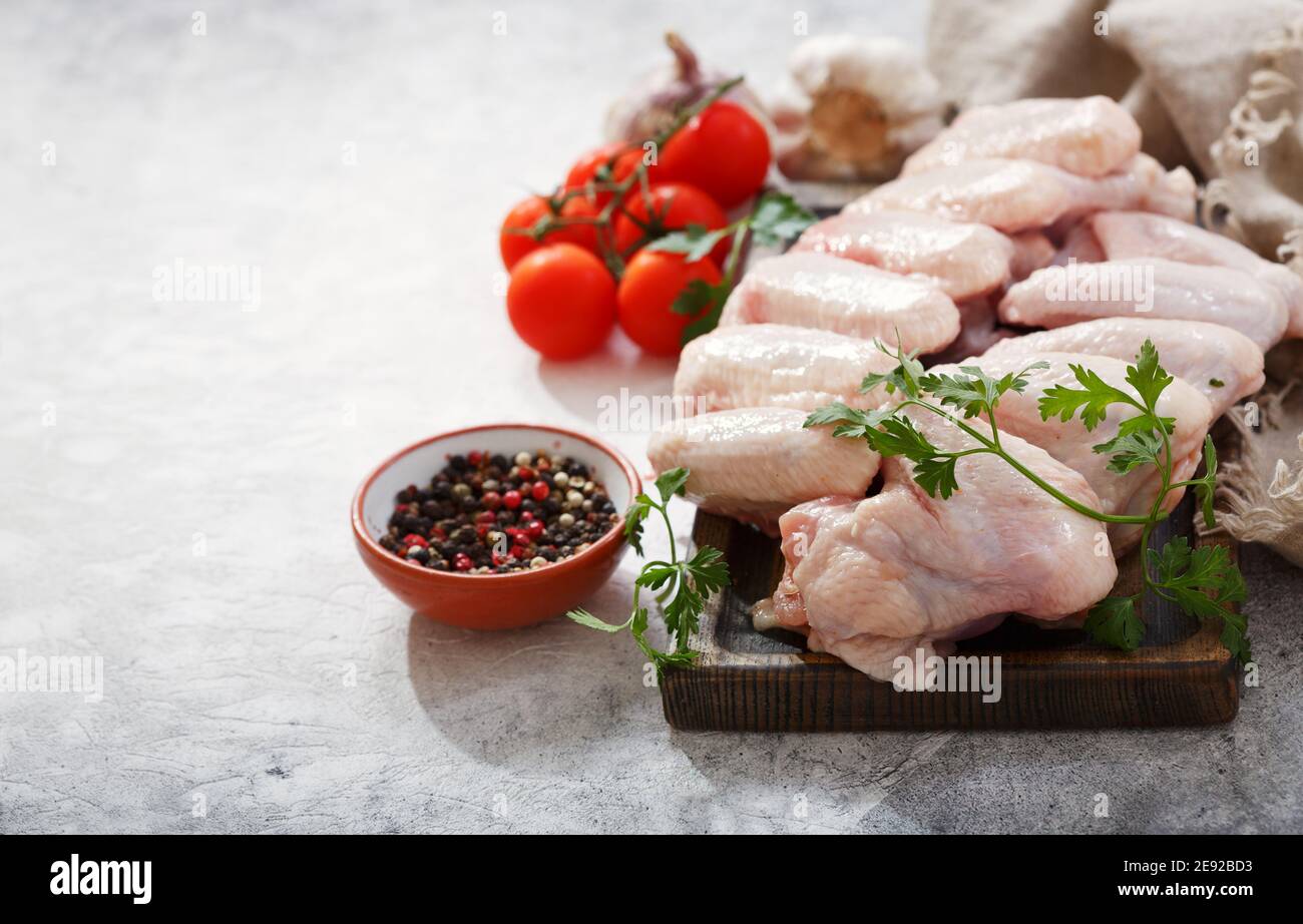 fresh chicken wings on wooden board with ingredients for cooking Stock