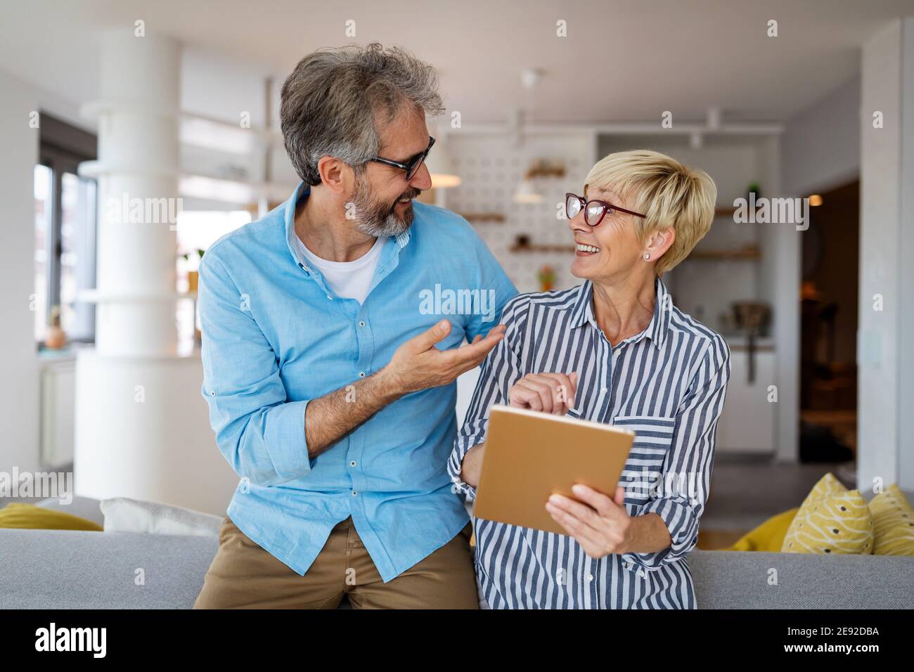 Lovely smiling mature couple having fun while using tablet at home Stock Photo