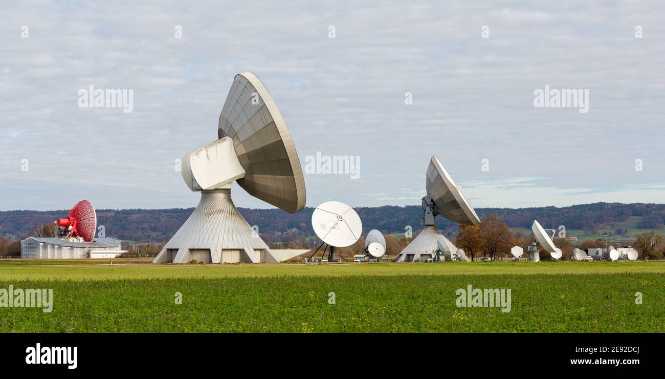 Raisting, Germany - Nov 13, 2020: Side view on several satellite dishes. Pointing towards the sky. Panorama format. Stock Photo