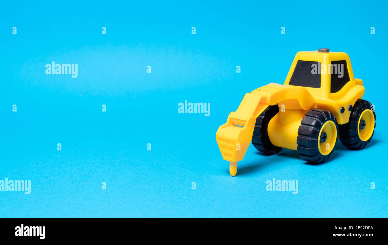 Toy tractor drill on a blue background with a place for text, a banner for a children's toy store. Stock Photo