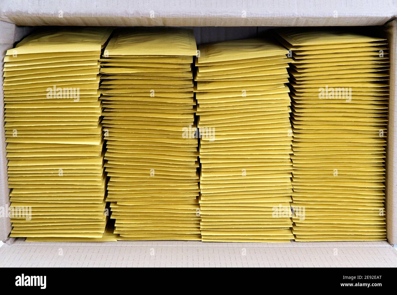 Four stacks of yellow mailing envelopes in a shipping box Stock Photo