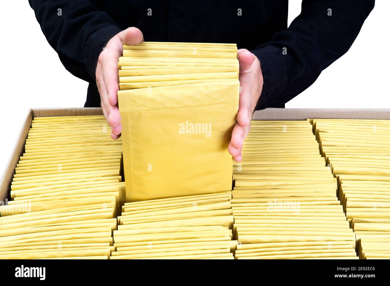 Man in black uniform packing yellow padded bubble envelopes in a large cardboard box Stock Photo