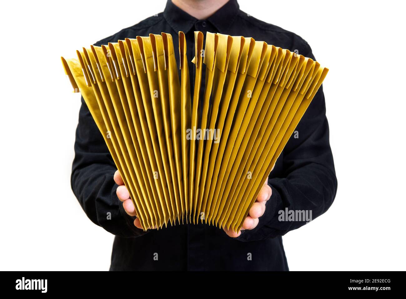 Man in black uniform holding a stack of yellow bubble envelopes isolated on white Stock Photo