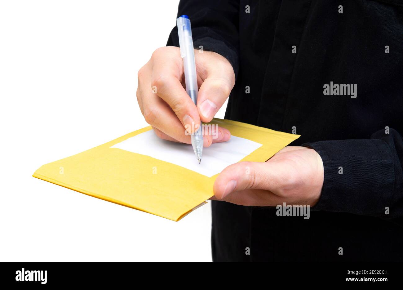 Man in a black uniform writes an address on a yellow padded envelope isolated on white Stock Photo