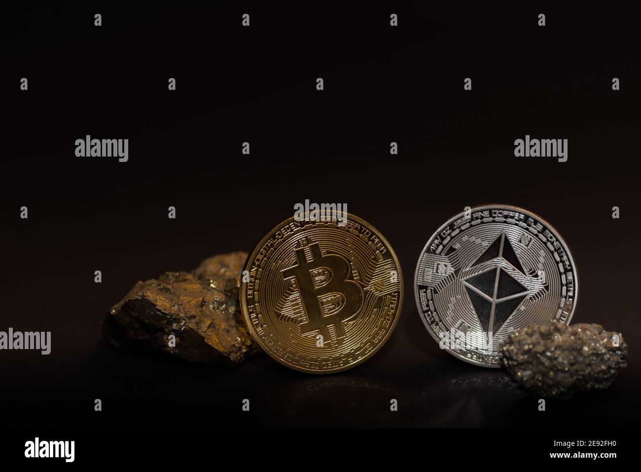single bitcoin and ether coin with minerals with iron on black ...