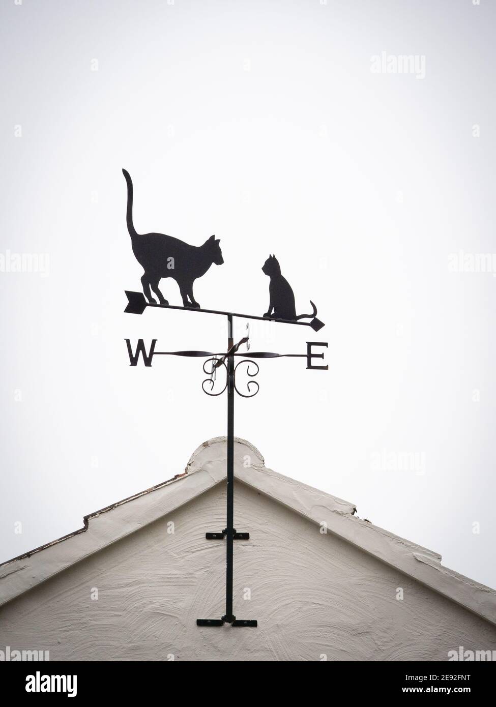 Weather vane decorated with two cats. One sitting and one standing with tail in the air. Stock Photo