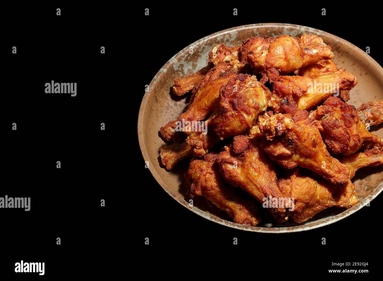 Fried chicken with fish sauce, several pieces on a plate. The black background has a place to place the text. Stock Photo