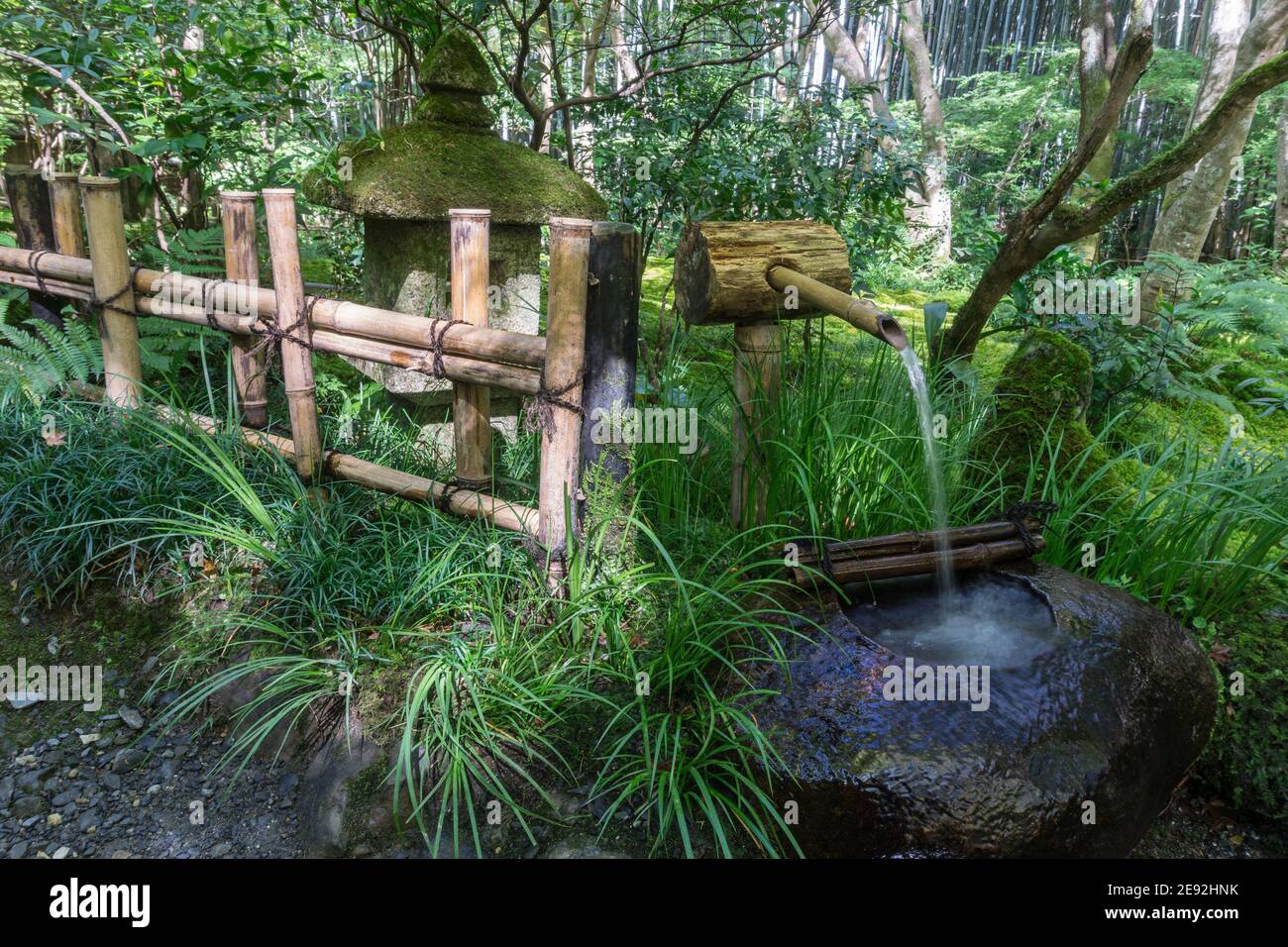 A traditional Japanese water fountain and basin, beside a bamboo fence at Gio-ji Temple in Arashiyama, Kyoto Stock Photo