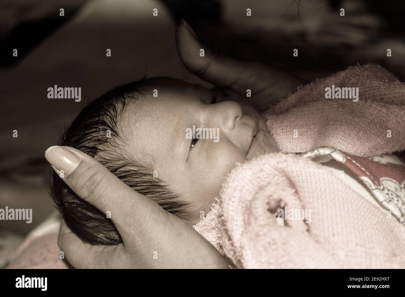 Beautiful Newborn baby boy closeup (6 days old) lying in mother lap in prenatal hospital. Kid wrapped in baby blanket (warm clothing) smiling and look Stock Photo