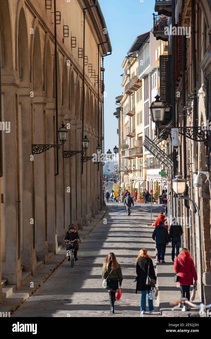 Florence, Italy - 2020, January 18: People walking in the streets, along the arches of the Corridoio Vasariano, in a sunny day. Stock Photo