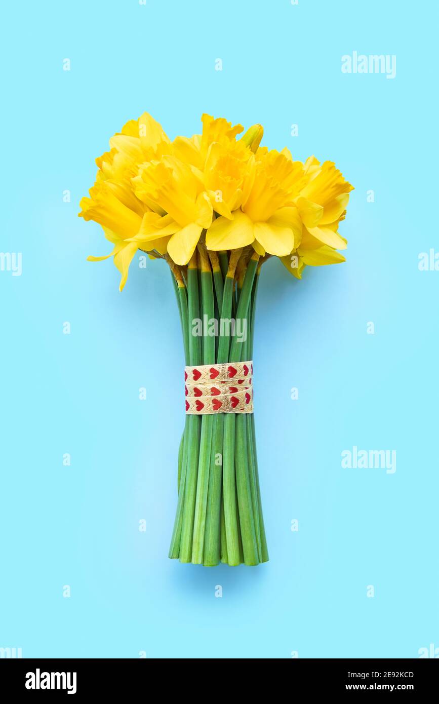 Bouquet of yellow narcissus decorated with ribbon with hearts on light