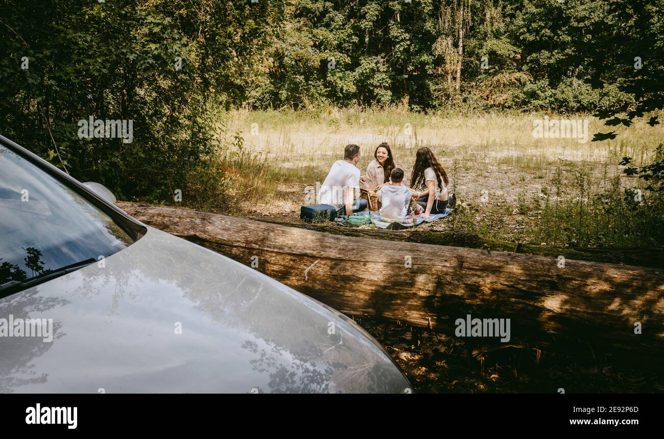 Family spending leisure time while sitting in forest during vacation Stock Photo