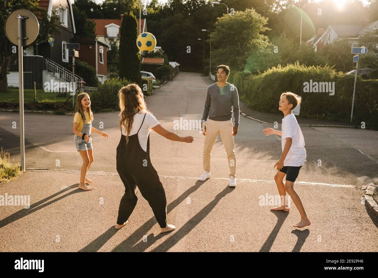 Happy family playing with soccer ball on road Stock Photo - Alamy