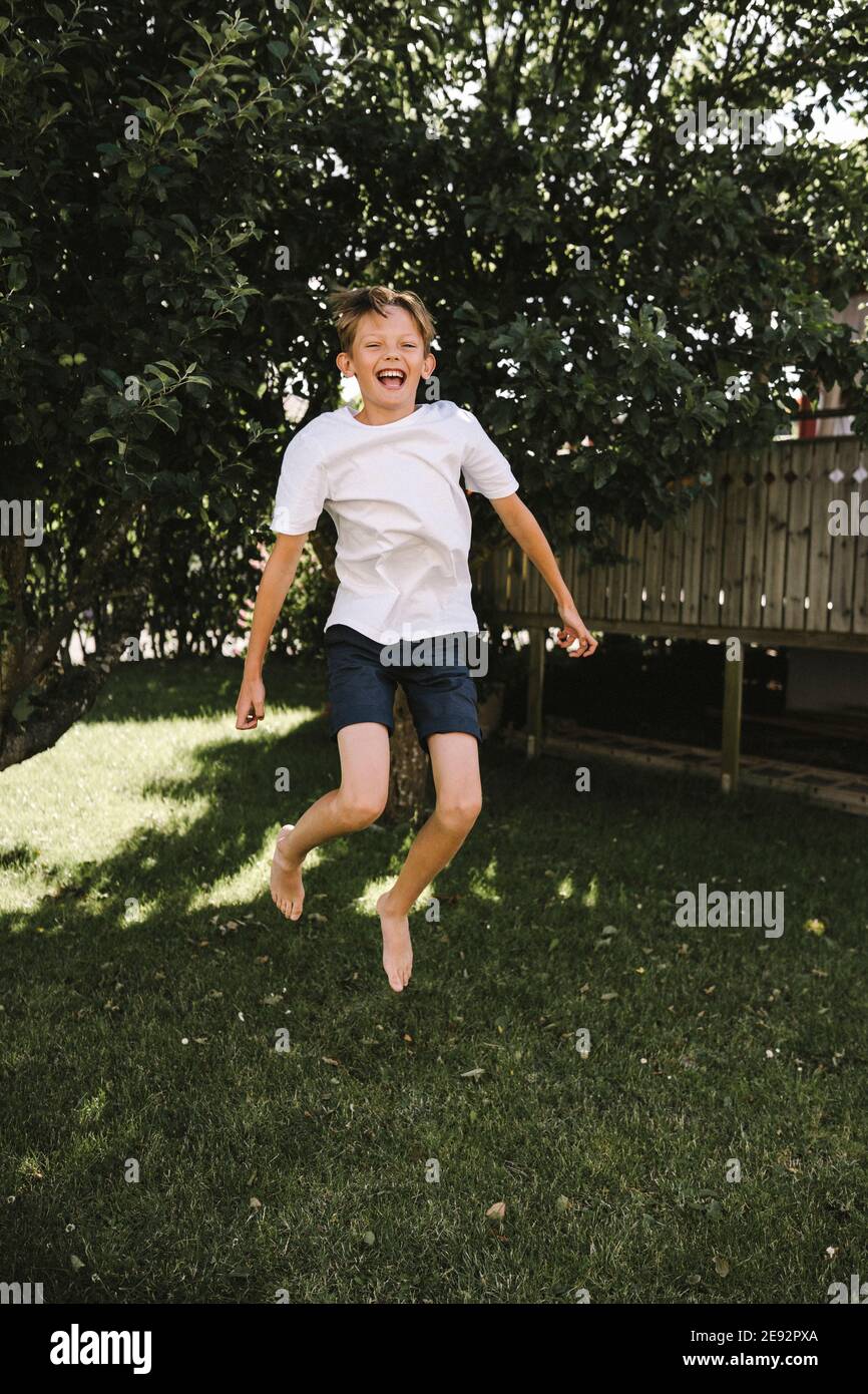 Cheerful boy jumping in back yard Stock Photo