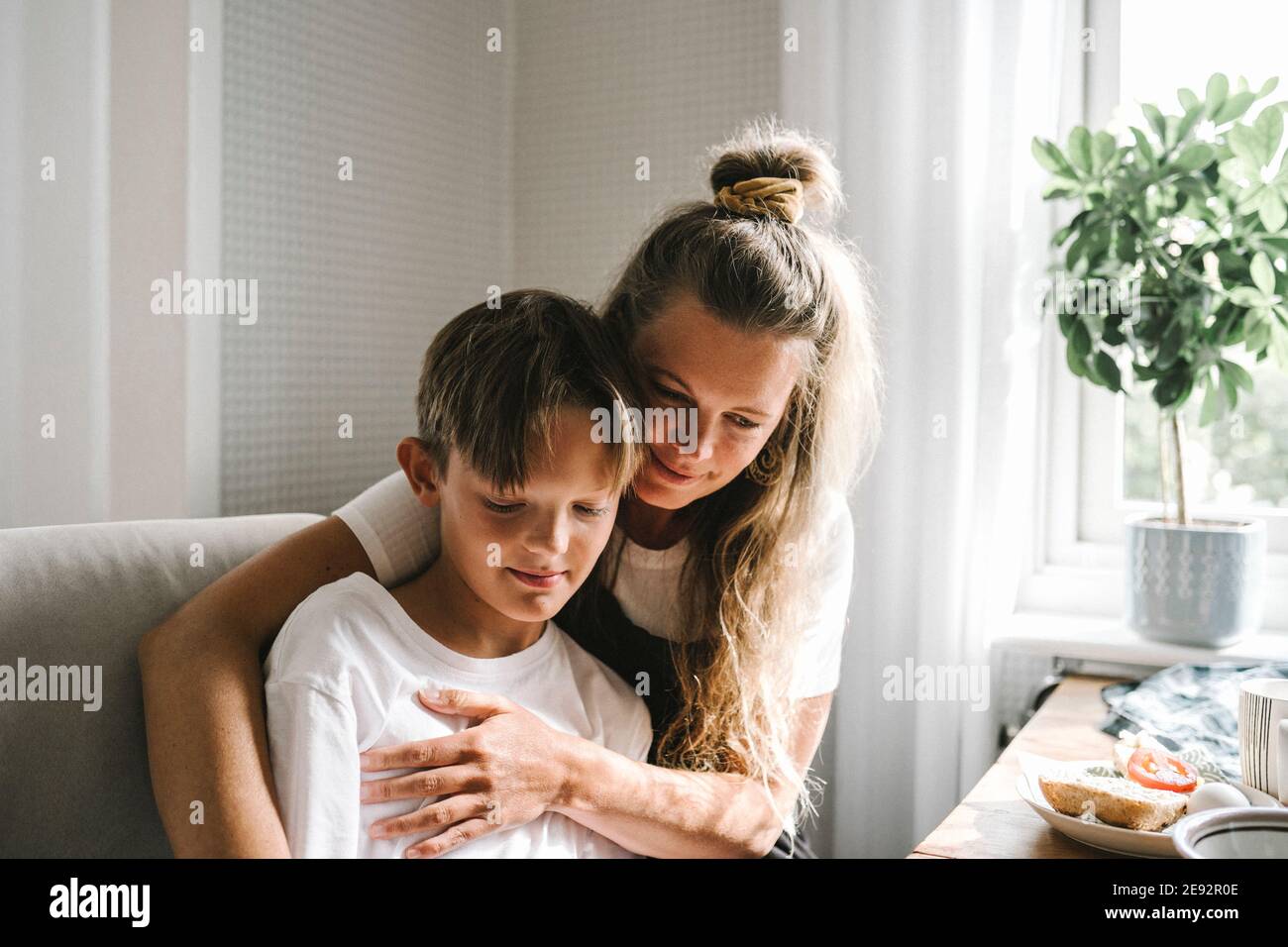 Smiling mother embracing son at home Stock Photo
