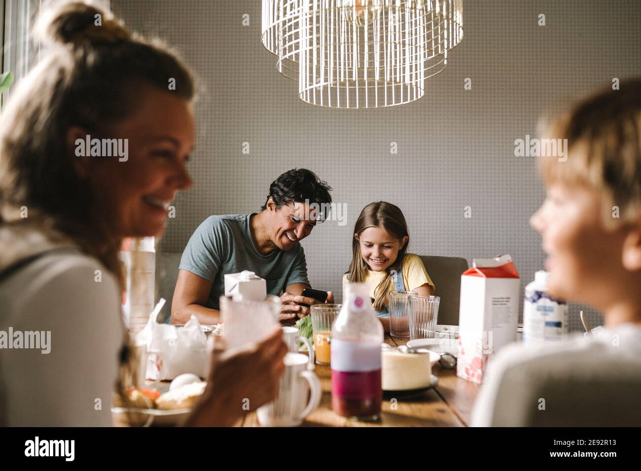 Happy father and daughter using smart phone at dining table Stock Photo