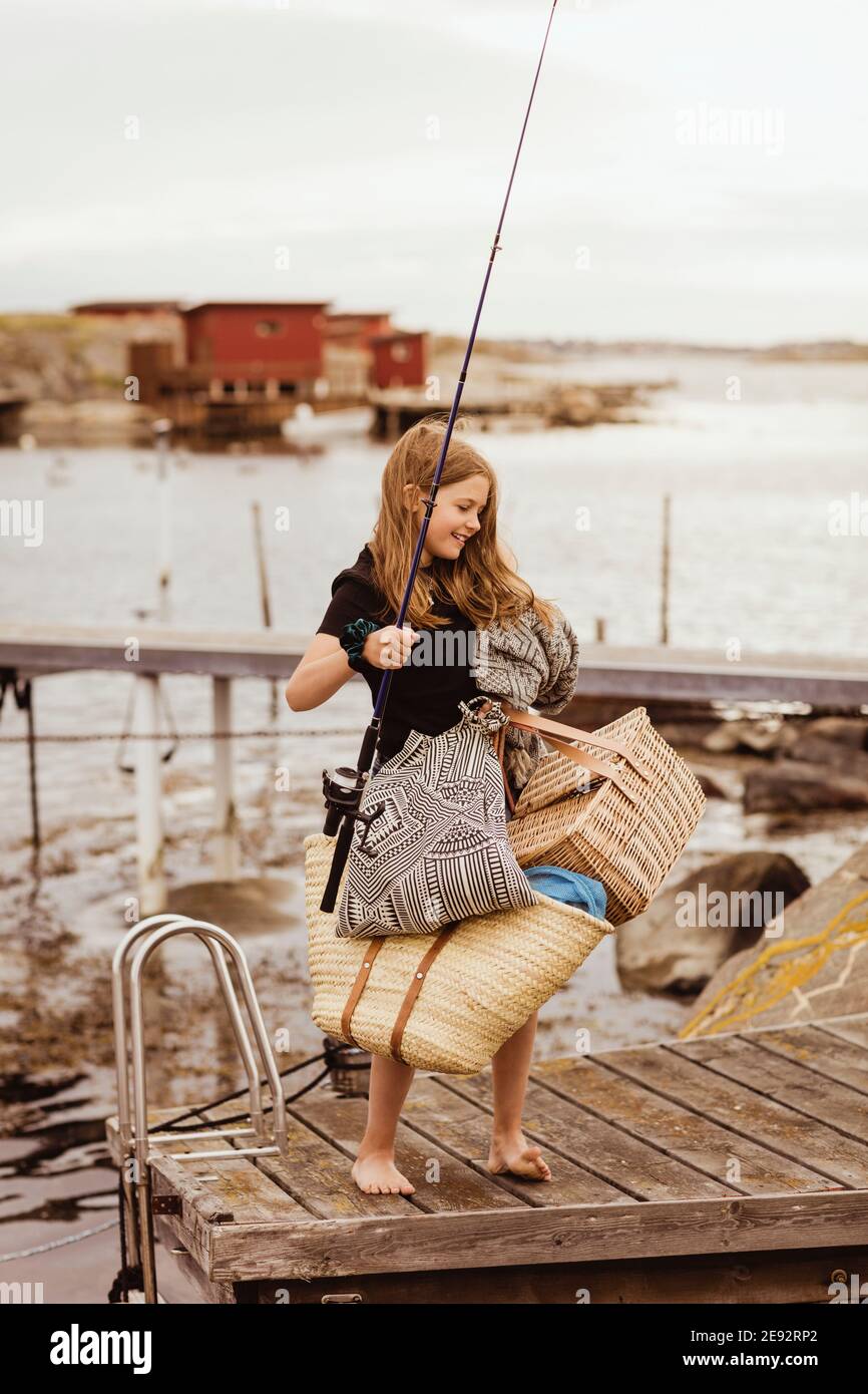 Pre-adolescent girl with picnic things standing on jetty Stock Photo