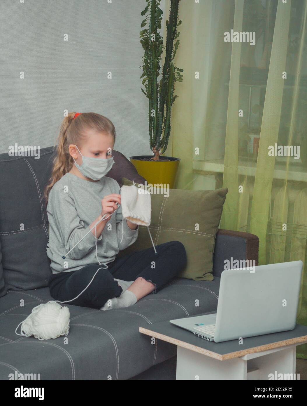 Girl learns knitting, watching instructional videos on a laptop Stock Photo