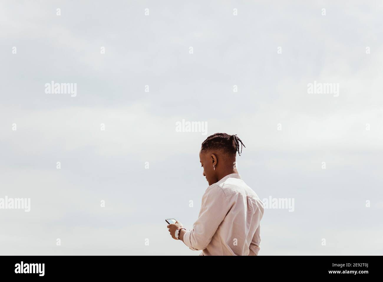 Young man using smart phone against clear sky on sunny day Stock Photo