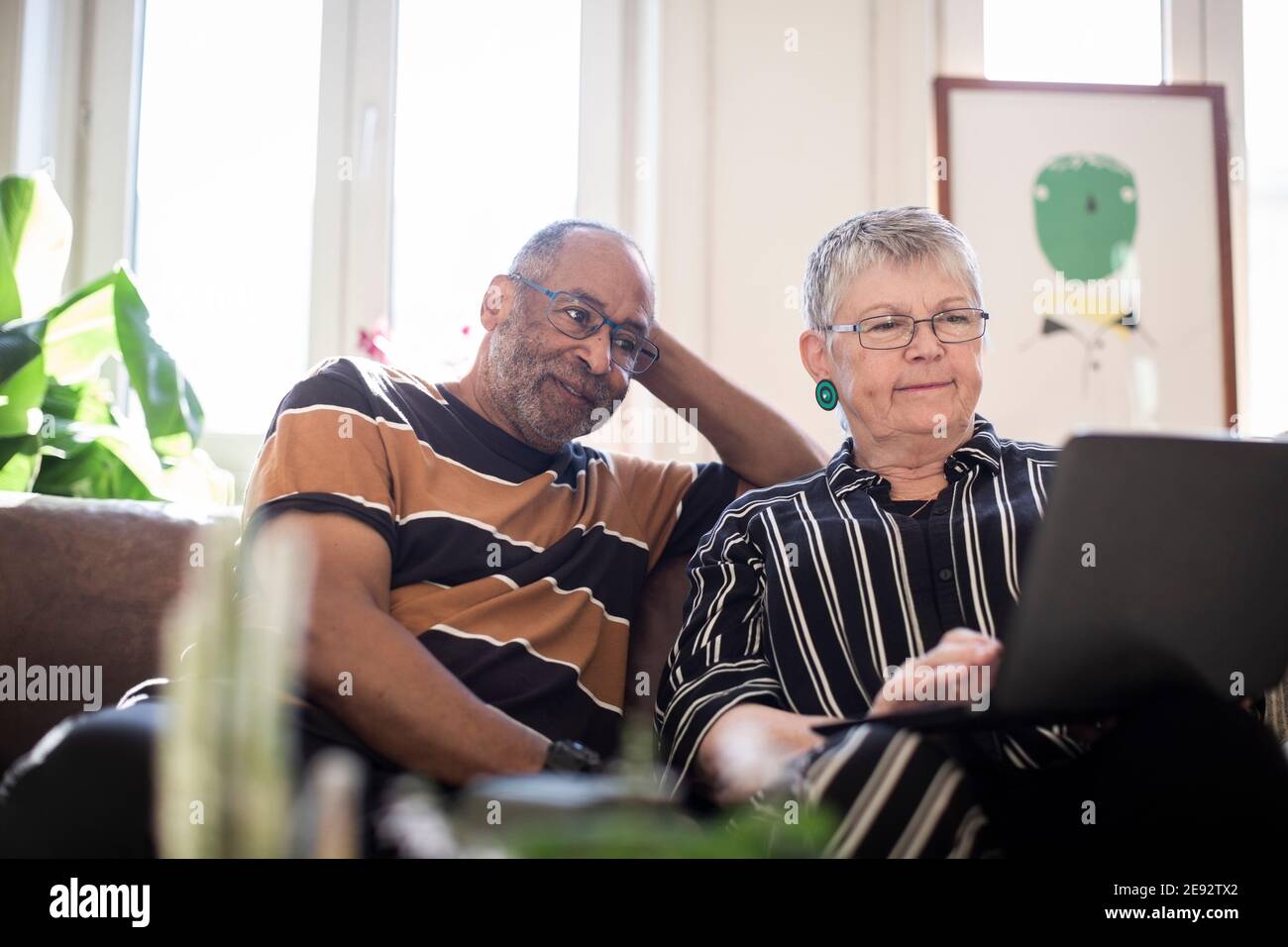 Woman using laptop while man sitting by on sofa Stock Photo