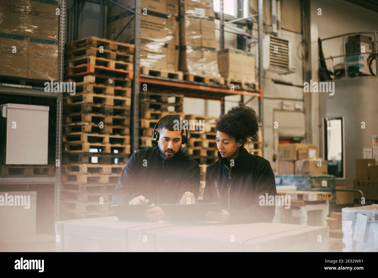 Businessman discussing with female colleague while using digital tablet at warehouse Stock Photo