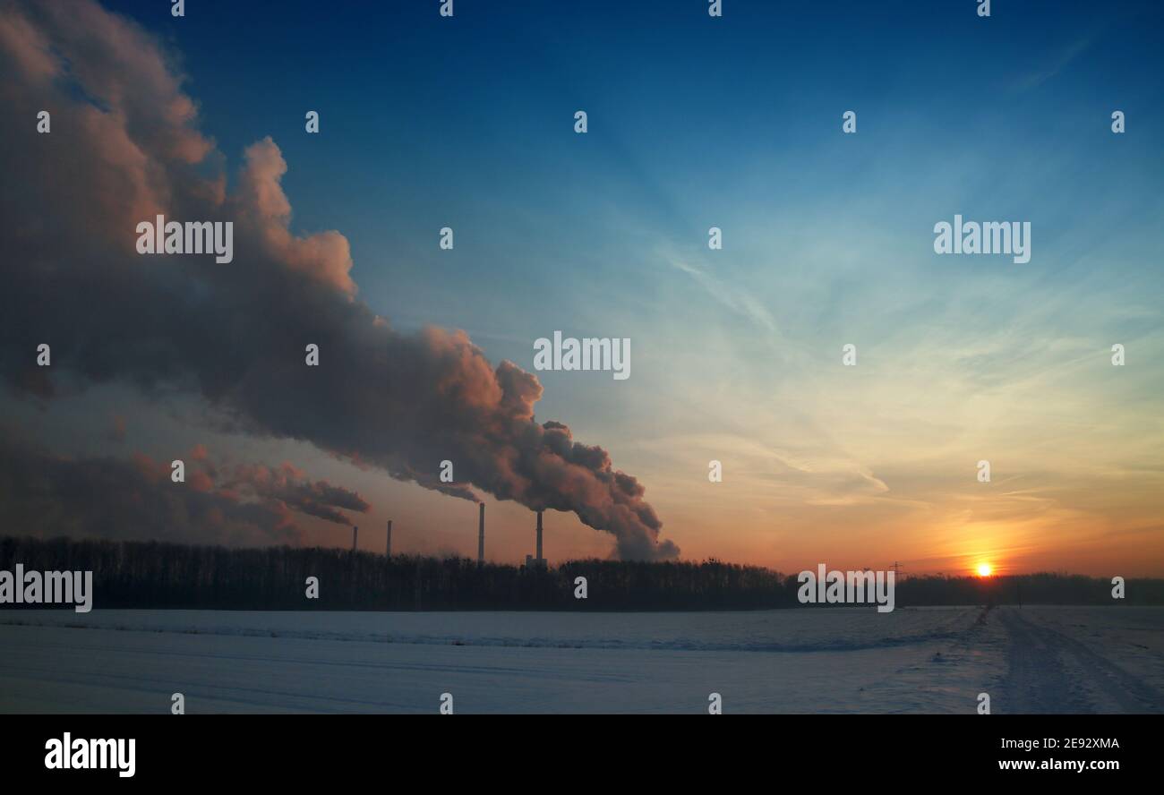 Steam from the factory at sunrise in winter Stock Photo