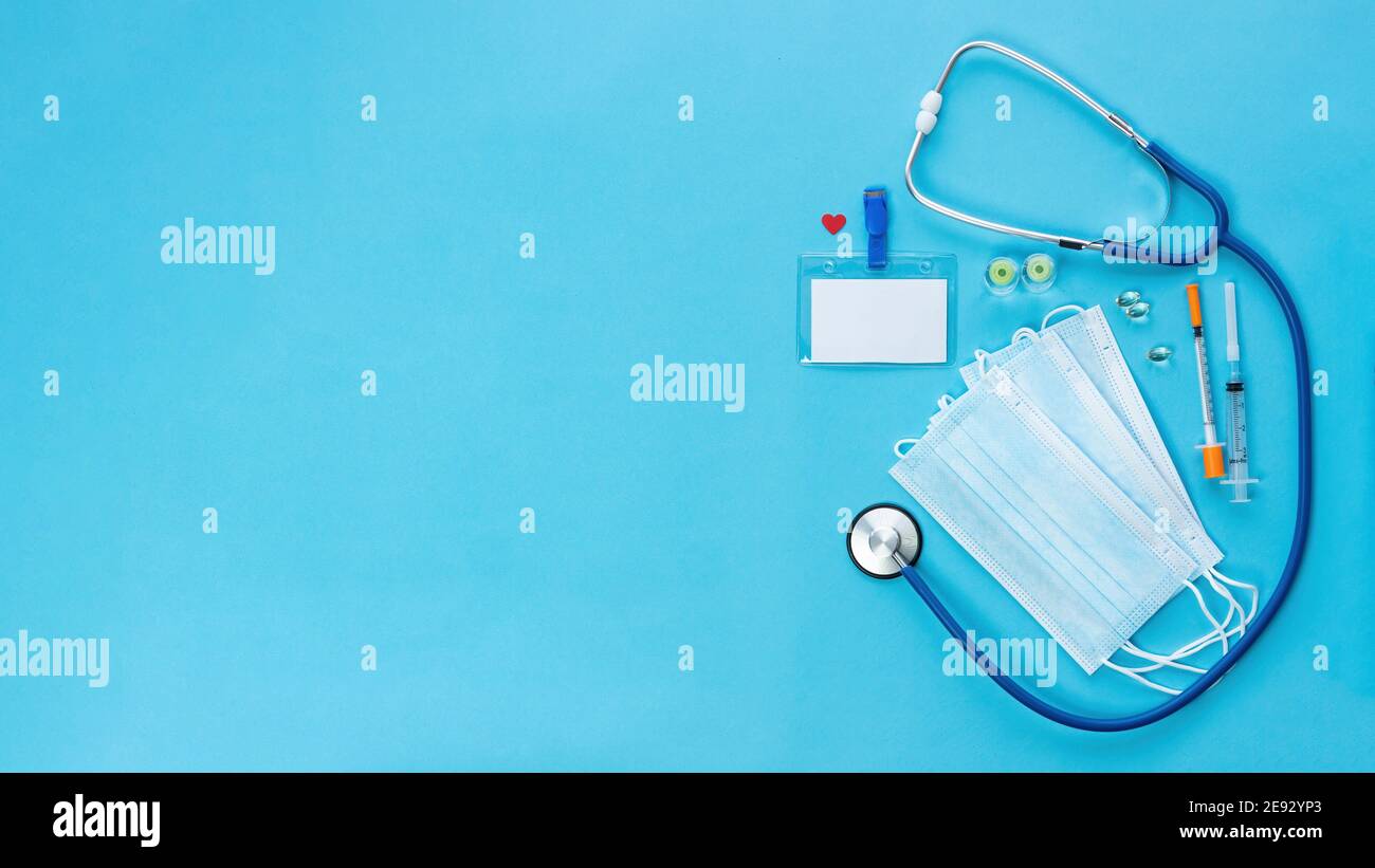 Promotional banner with medical items and blank doctor badge on blue background with copy space. COVID-19 coronavirus vaccination concept banner. Heal Stock Photo