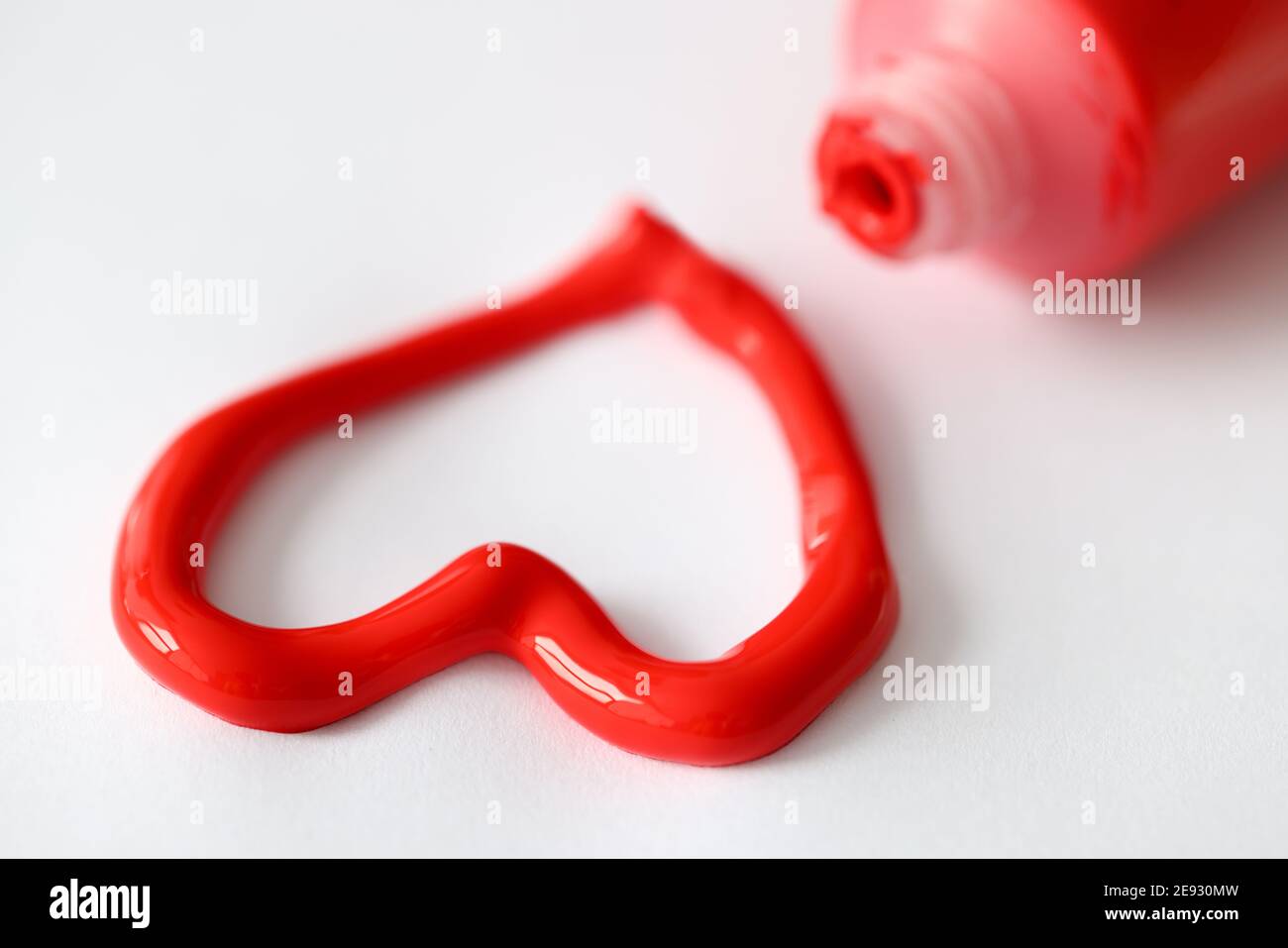 Red paint squeezed out of tube in shape of heart closeup Stock Photo