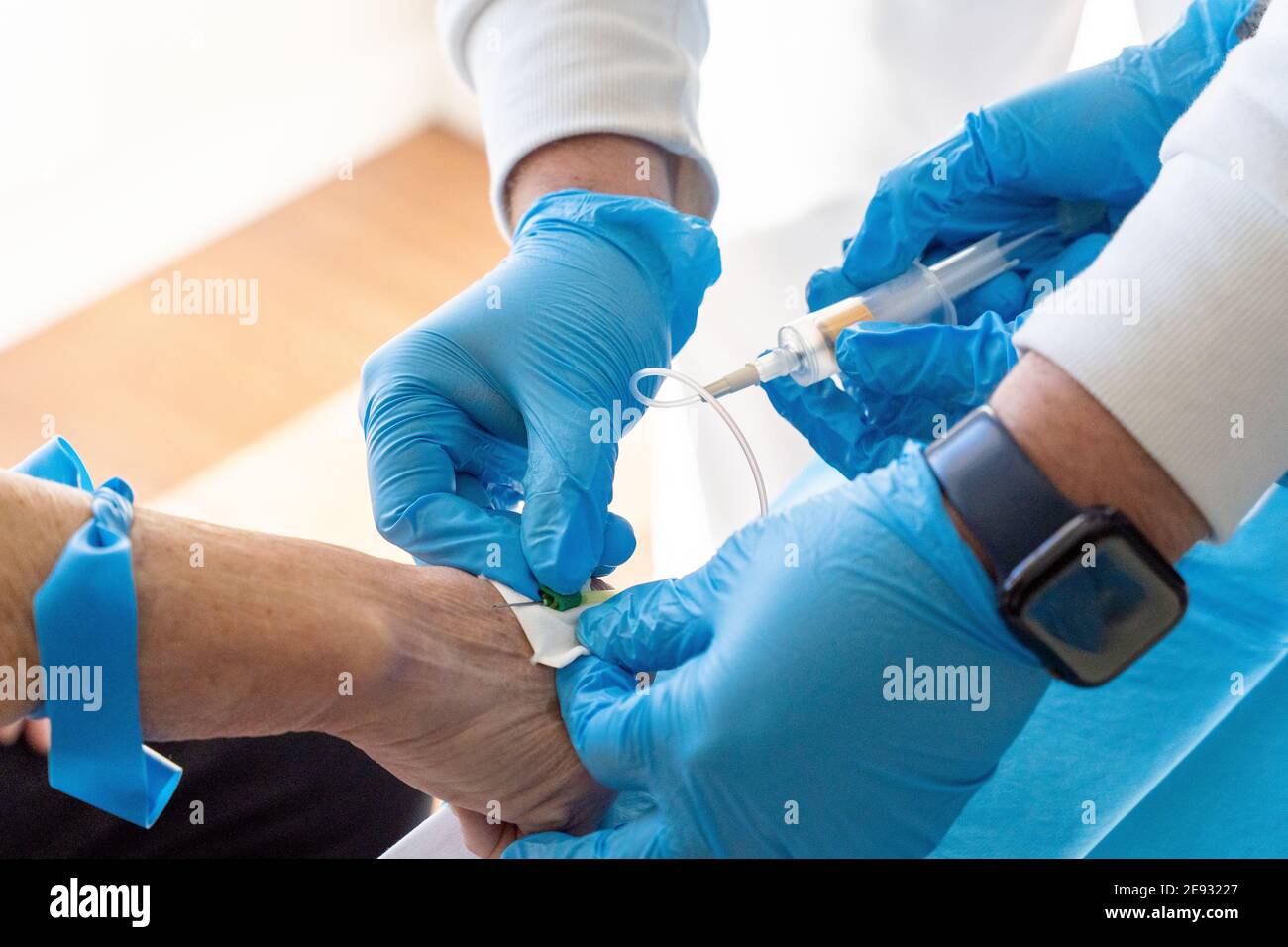 From above of crop anonymous doctors with needle and syringe taking blood sample from elderly female patient Stock Photo