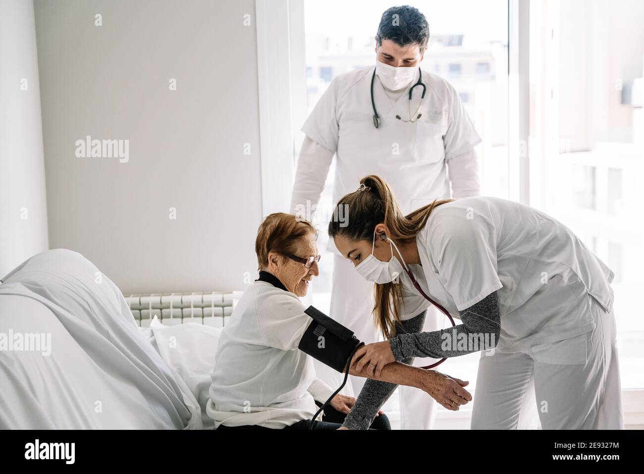 Doctors in medical masks using tonometer and measuring blood pressure
