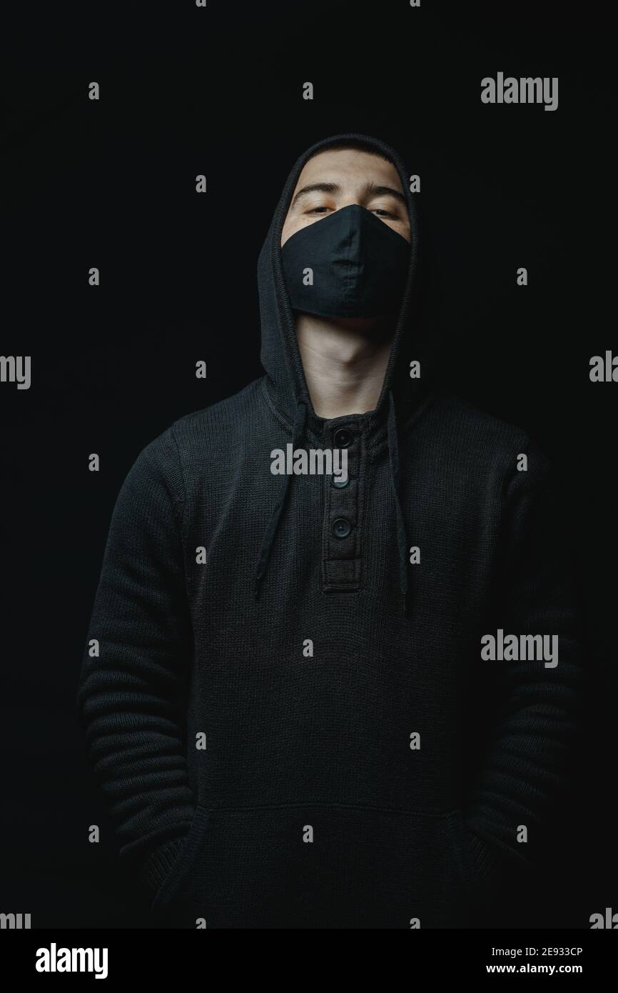 young cool rapper with black hoodie and face mask standing in front of black  background Stock Photo - Alamy