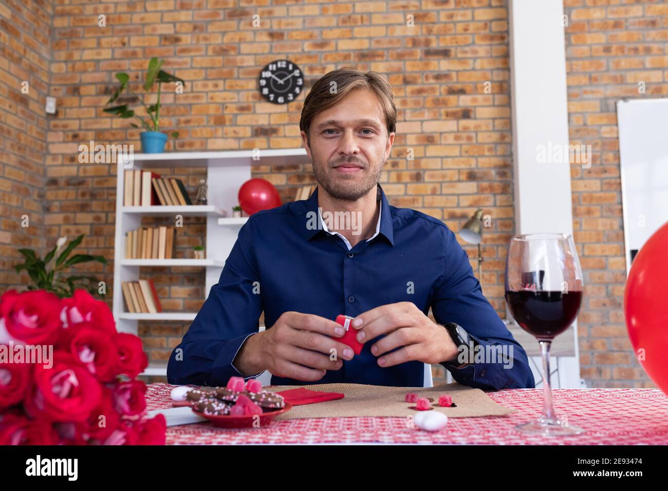 Caucasian man making video call opening a small gift box and smiling Stock Photo