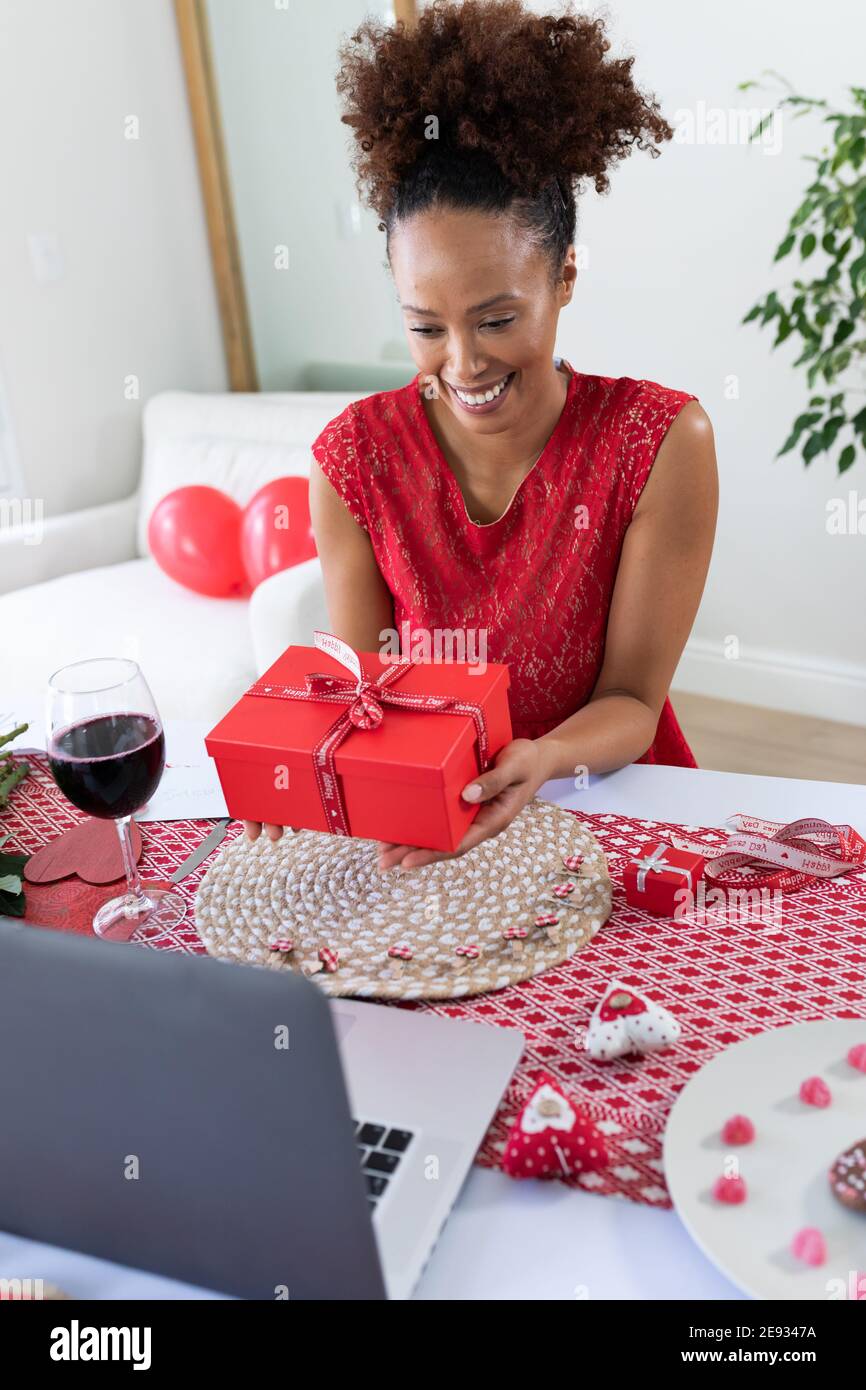 African american woman holding gift box on videocall at home Stock Photo