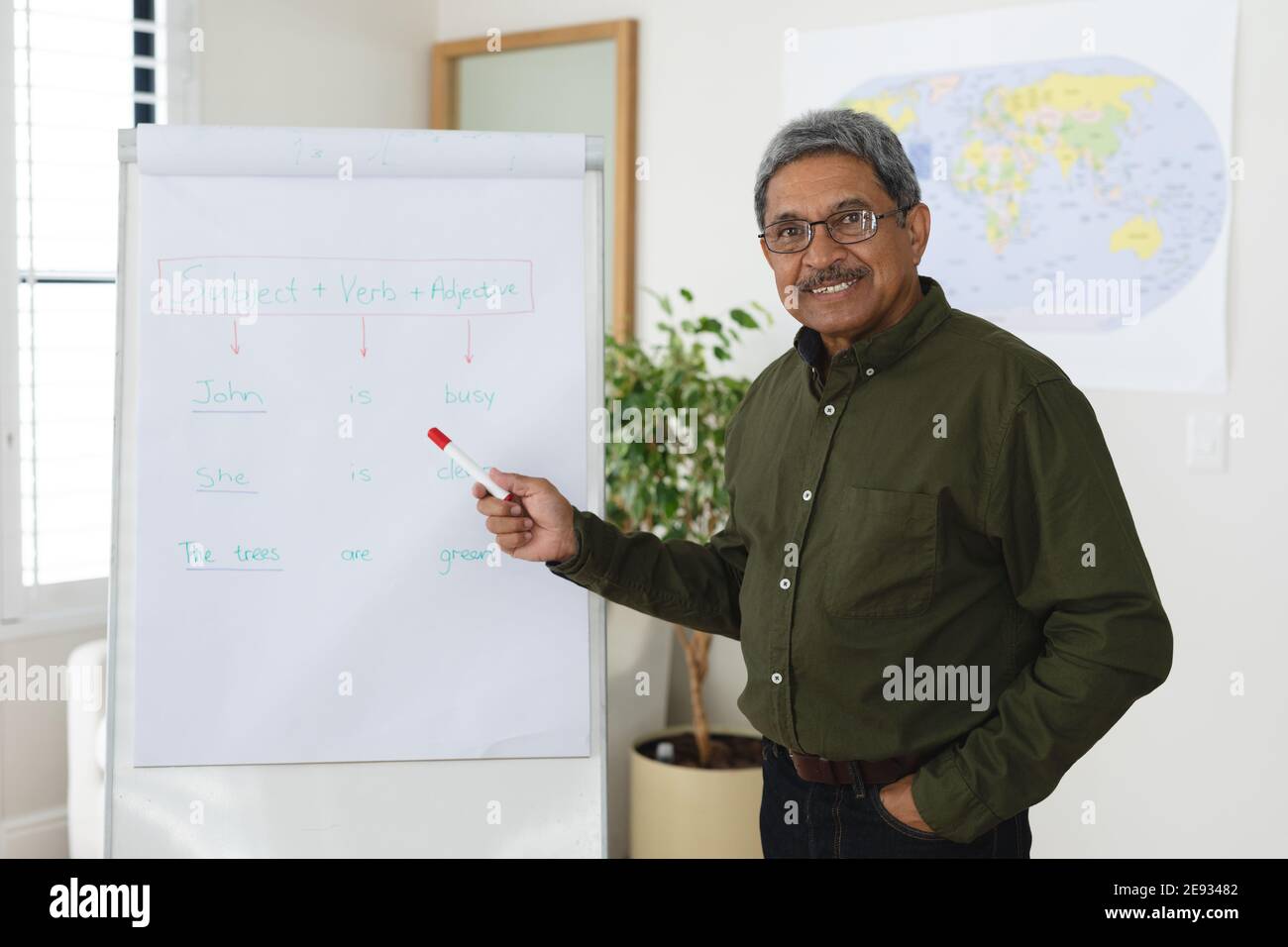 Mixed race male english teacher standing at a whiteboard giving an online lesson to camera Stock Photo